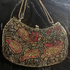 Intricate beaded bag with back and red accents, with gold Chain.